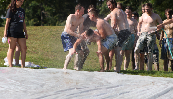 A group of young men throw another young man onto a tarp.