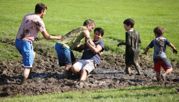 A group of young men and boys playing in a mud pit.
