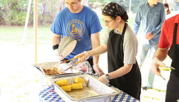 A couple young men setting up to serve food.