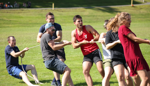 A group of young men and women playing tug of war.