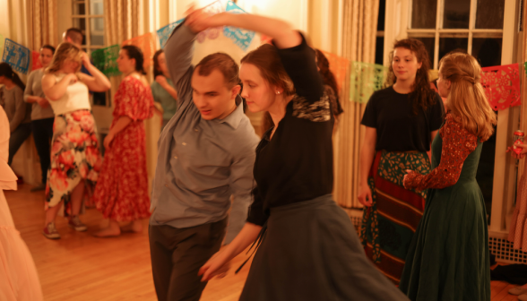 Open house visitor dances with a student