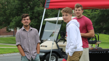 A regular student, a summer programmer, and a prefect chat beside the registration tables 
