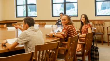 Students await the start of class around the seminar table