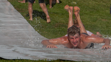 A student in swimwear speeds down the waterslide, head-first