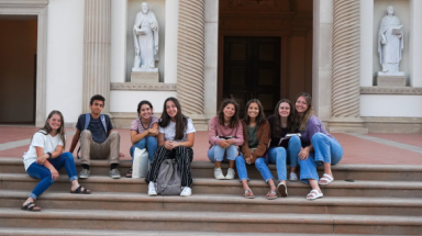 A group of eight students seated on the Chapel steps