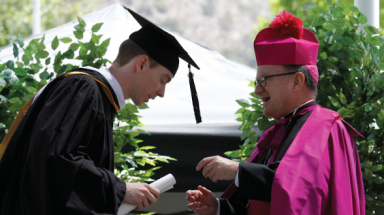 Bishop Barber presents a diploma to a student
