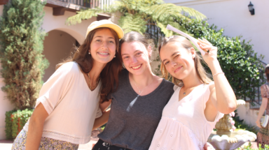 Three pose for a photo outside the dorm