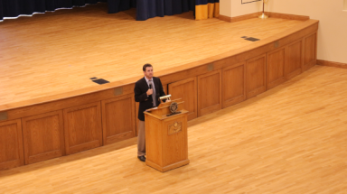 Dr. Cooper delivers a lecture at the podium in St. Cecilia's