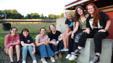 Seven pose for a photo by the snack shop at the drive-in theater