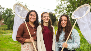 Three pose outdoors with their nets
