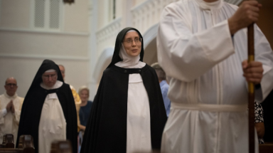 Sr. Maria Barrett processes in behind the crucifer