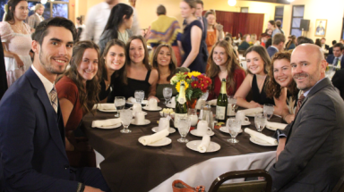 Nine at a table pose for a photo