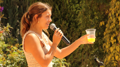 A student raises her glass for a toast, mic in hand