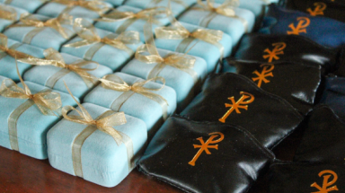 Small baby-blue boxes and rosary pouches await blessing