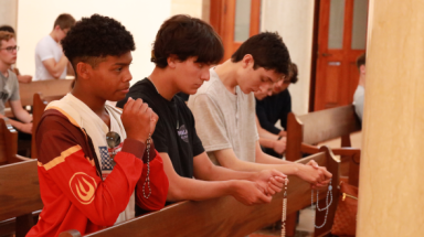 Three in a pew praying the Rosary