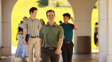 Happy students walk down the arcade