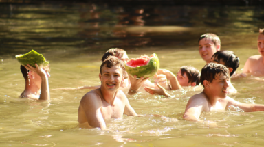 Several hold pieces of the broken watermelon in the pond