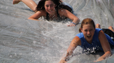 Two students slide down the slip n' slide