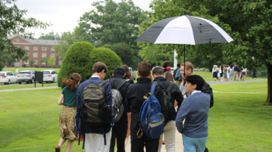 Students walk across campus under an umbrella