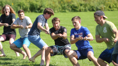 A group of concenrated young men playing tug of war.
