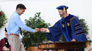 A student shakes the registrar's hand