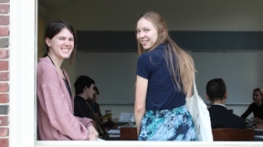 Two New England students look out a window