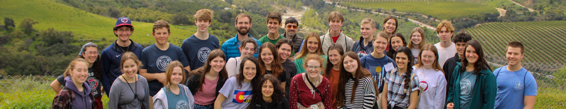 A group of students poses in the green hills around campus