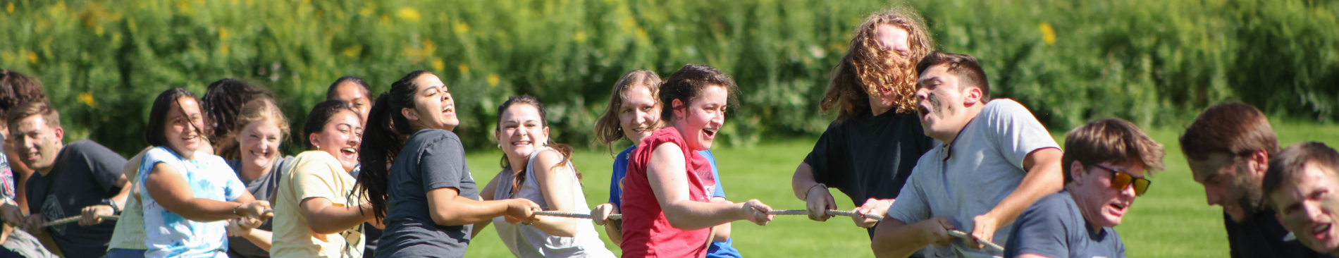 A group of smiling students playing tug of war.