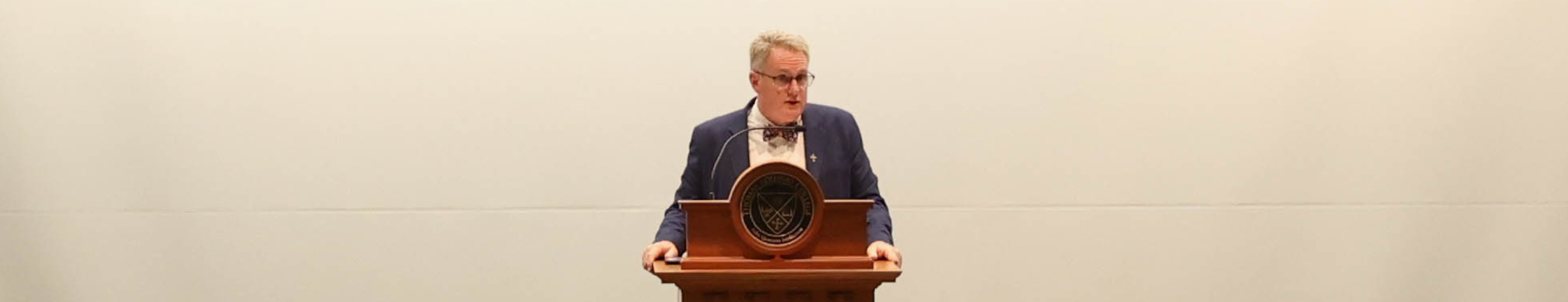 A man standing behind a podium, looking slightly to his left.