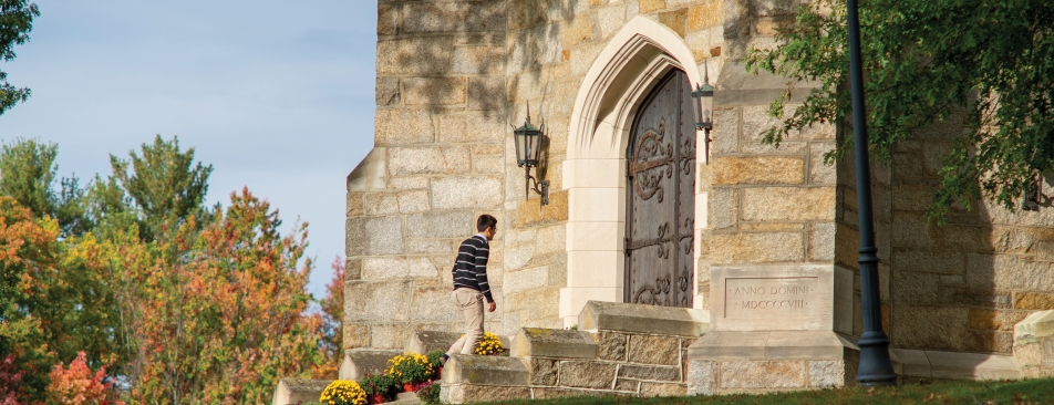 Man walking up to a big iron door of a brick building