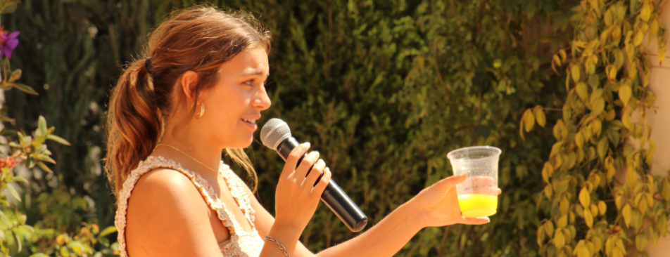 A student raises her glass for a toast, mic in hand