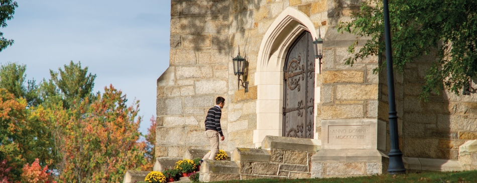 Man walking up to a big iron door of a brick building